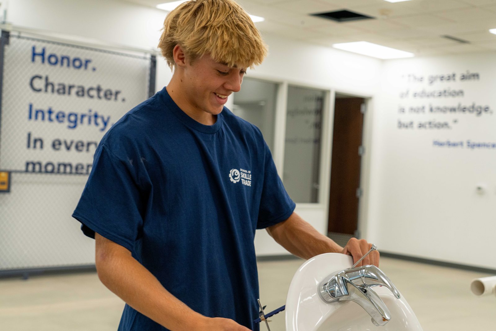 Student installing a faucet on a sink during hands-on plumbing training